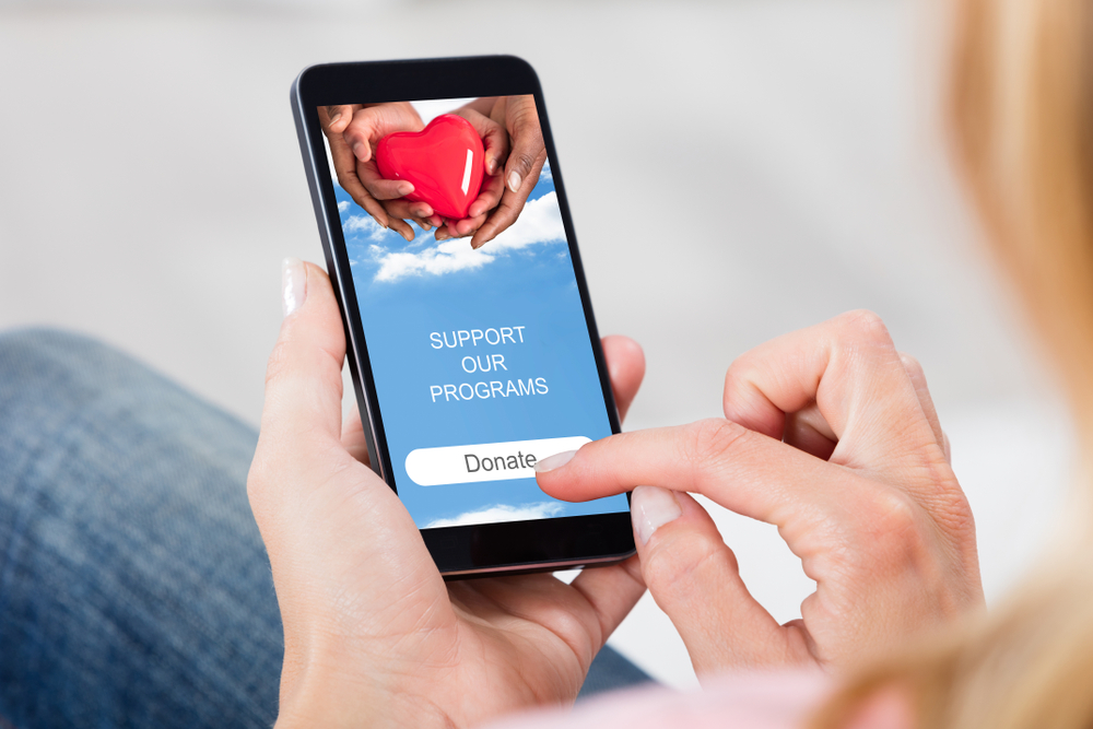 Close Up Of A Person's Hand Donating Money On Smartphone